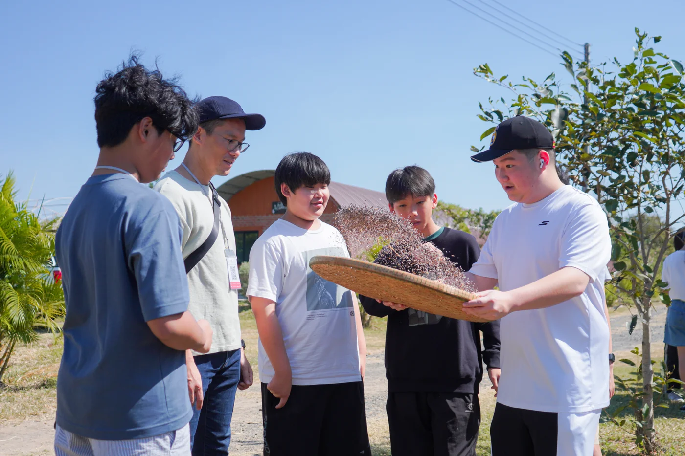 Students taking part in a hands-on grain-winnowing workshop outdoors