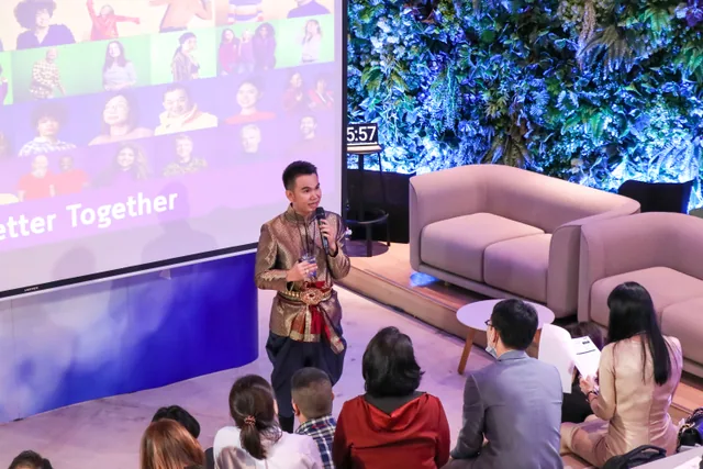Phudit speaking to an audience beside a presentation screen